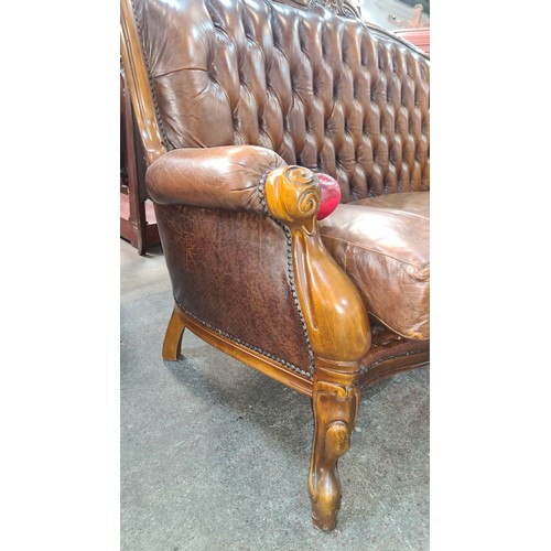 915 - Star lot :A Victorian-style button-tufted leather sofa with ornately carved wooden frame, rolled arm... 