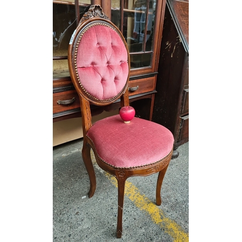 A Victorian-style chair with carved mahogany frame and pink tufted upholstery. Features decorative brass stud trim and elegant cabriole legs.