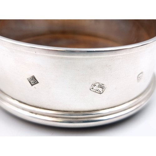 60 - A sterling silver bottle coaster hallmarked London with a wooden baize base. Dimensions - 9cm diamet... 