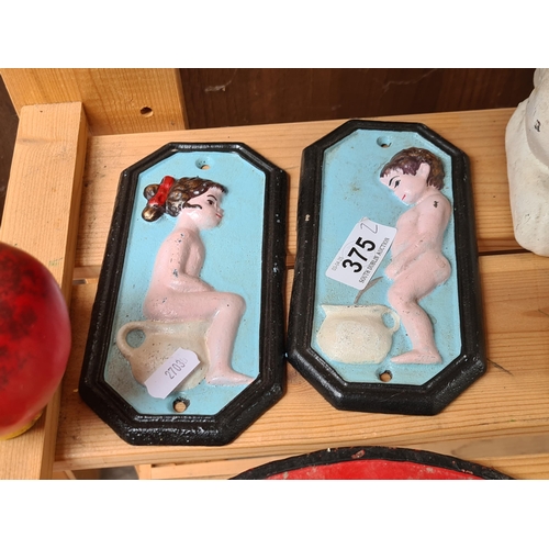 A pair of painted cast iron metal wall sign for ladies and gents loo.