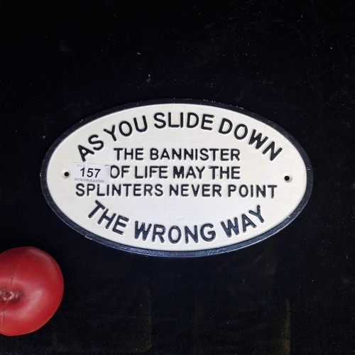 A painted cast metal wall plaque reading 'As You Slide Down The Bannister Of Life May The Splinters Never Point The Wrong Way'.