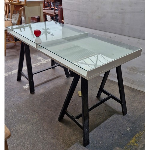 A white Ikea Desk top with glass panel and a pair of IKEA “VIKA
