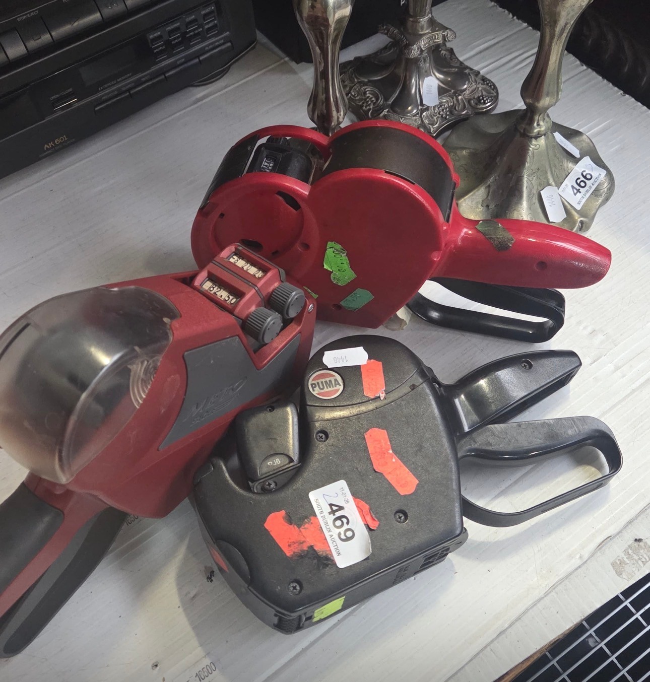 Three handheld price label guns, red and black moulded plastic with ...