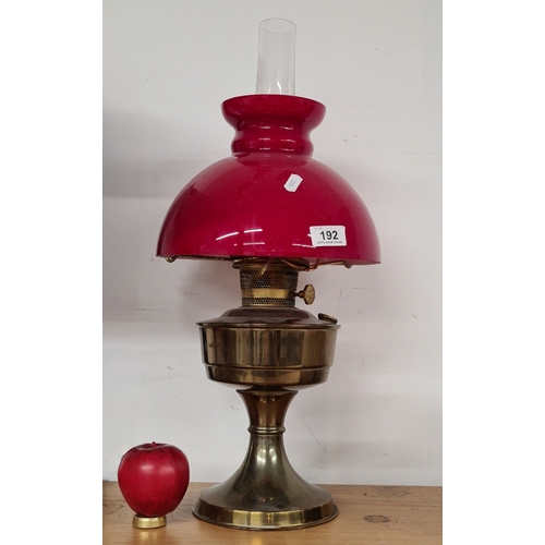 192 - A vintage 'Aladdin' brass oil lamp with bright red glass shade and hurricane glass chimney. Attracti... 