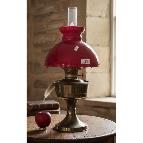 192 - A vintage 'Aladdin' brass oil lamp with bright red glass shade and hurricane glass chimney. Attracti... 