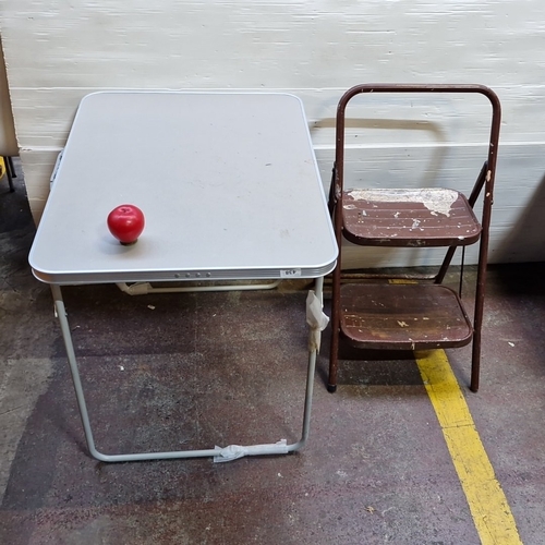 438 - Set of 2: a folding rectangular table with grey top and tubular metal frame, together with a two-ste... 