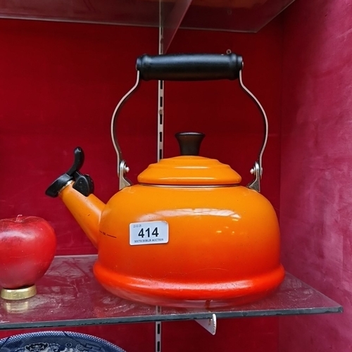 414 - A Le Creuset orange enamelled metal whistling kettle, 1.6L (1.7Qt) capacity, with black phenolic han... 