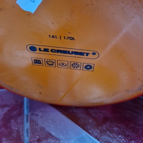 414 - A Le Creuset orange enamelled metal whistling kettle, 1.6L (1.7Qt) capacity, with black phenolic han... 