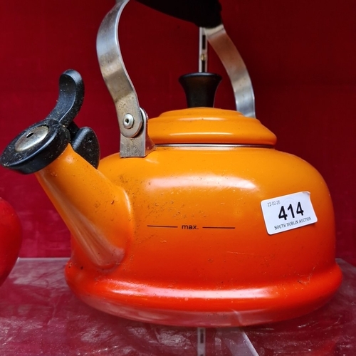 414 - A Le Creuset orange enamelled metal whistling kettle, 1.6L (1.7Qt) capacity, with black phenolic han... 