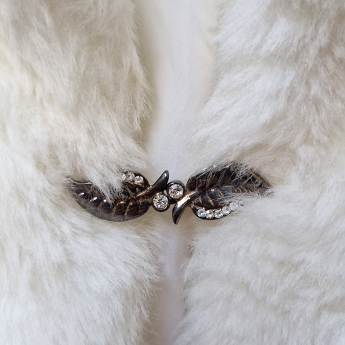 423 - A white faux-fur short cape or jacket, with broad collar and cropped sleeves, lined in white, and fa... 