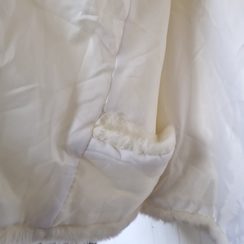 423 - A white faux-fur short cape or jacket, with broad collar and cropped sleeves, lined in white, and fa... 