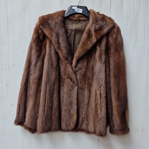 427 - A brown fur jacket with broad notched lapels and satin lining, bearing embroidered Grosvenor and Swi... 