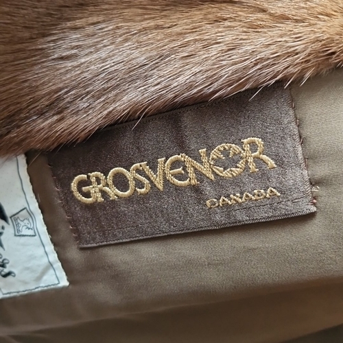 427 - A brown fur jacket with broad notched lapels and satin lining, bearing embroidered Grosvenor and Swi... 