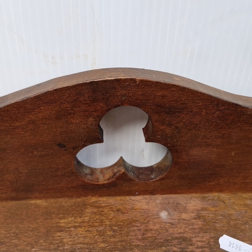 447 - A wooden wall-mounted shelf rack with three graduated tiers, shaped side supports, and a pierced tre... 