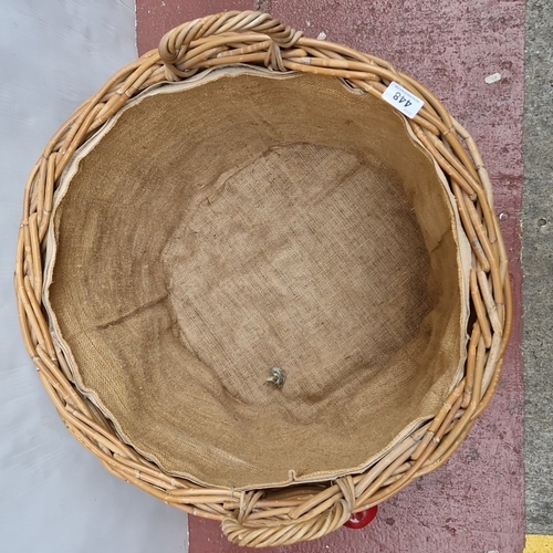 448 - A large woven wicker log basket, of oval form with twin loop handles and hessian-lined interior.
