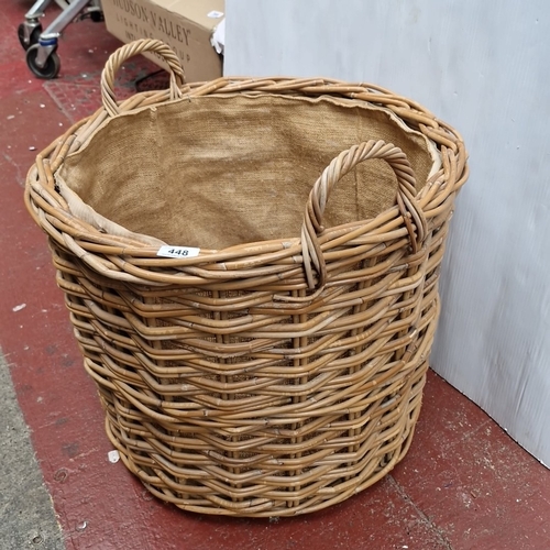 448 - A large woven wicker log basket, of oval form with twin loop handles and hessian-lined interior.