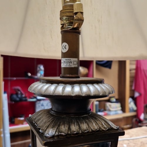 457 - A large cast-metal table lamp in the form of a glazed lantern, with fluted galleries and an ecru bel... 