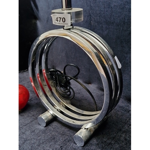 470 - A modern chrome table lamp, the circular openwork base formed of concentric rings on twin feet, with... 