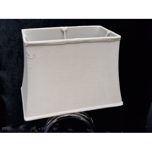 470 - A modern chrome table lamp, the circular openwork base formed of concentric rings on twin feet, with... 