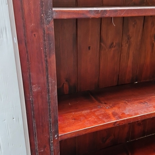 482 - A tall pine open bookcase, the moulded cornice with scalloped apron above a boarded back and five ad... 