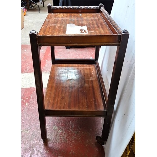 485 - A mahogany two-tier trolley table, with three-quarter gallery top carved with leaf-scroll and rosett... 