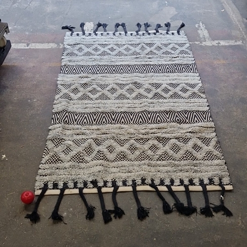 A modern flatweave cotton rug with raised tufted geometric bands in cream and black, finished with braided tassel fringe to both ends; the reverse with woven stripe pattern.
MM: 220cm X 120cm

Previous in auction on T022626  - 01/03/2026 with Lot no.714

Previous in auction on T050326  - 08/03/2026 with Lot no.1309