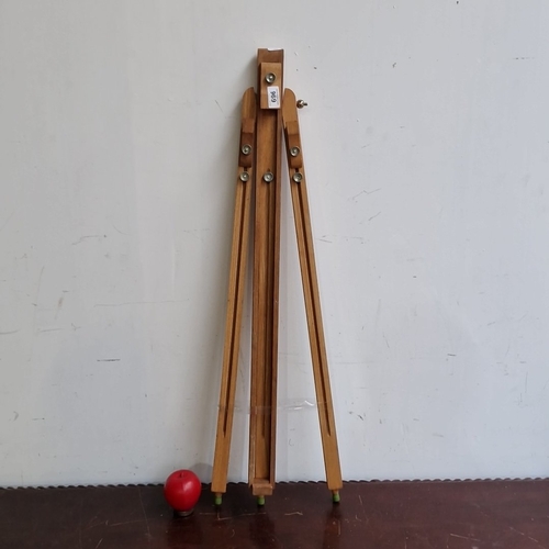 A folding wooden artist’s studio easel, with adjustable support and brass-coloured fittings, raised on three splayed legs with rubber feet.