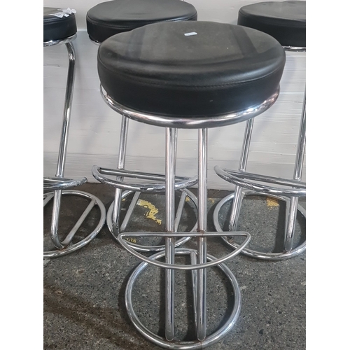 A group of 6 chrome-plated bar stools with round black upholstered ...