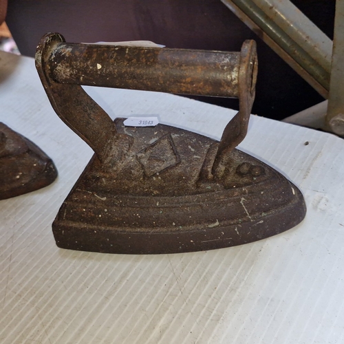 A pair of antique cast-iron flat irons, each of triangular form with ...