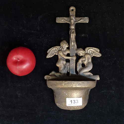 133 - A cast iron holy water font featuring a crucifixion scene with two kneeling angels.