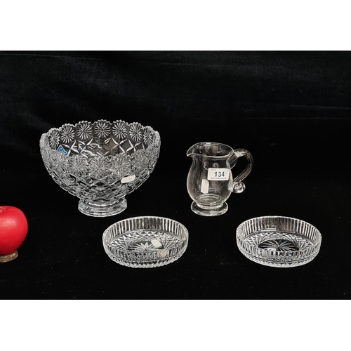 134 - Four glass and crystal pieces including two ash trays, a hand blown jug with pontil mark, and a larg... 