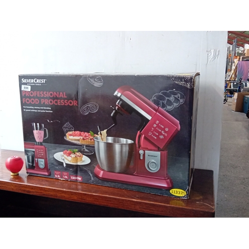 An as new large SilverCrest "Professional Food Processor" stand mixer in red, model SKMP 1300 B3 (IAN 113373/113374), with stainless-steel mixing bowl and assorted attachments including whisk, beater, dough hook, glass blender jug, and splash guard.