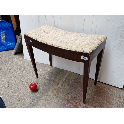 Mid-20th century mahogany occasional bench or stool, the rectangular upholstered seat in neutral woven fabric with brass studded trim, above a shaped apron and tapering square legs.