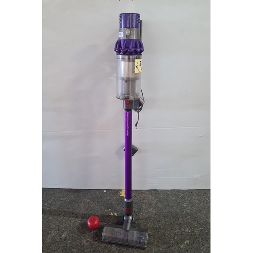 Dyson Cyclone V10 Animal cordless stick vacuum cleaner, with wall-mount charging dock and roller floorhead, in purple and grey moulded plastics with clear dust canister; bearing Dyson labels and serial number.