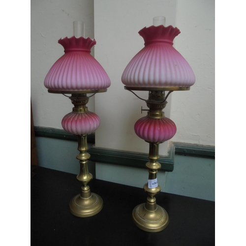 680 - A neat pair of candlestick styled oil lamps with pink oil container and shades with funnels.