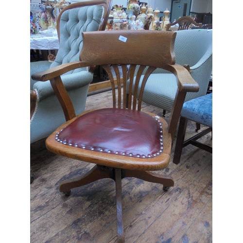 692 - Oak swivel office chair on casters with leather seat.