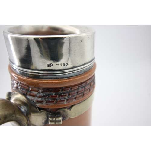 1334 - Doulton stoneware decorative jug having silver rimmed top and brass handle (some damage to base)