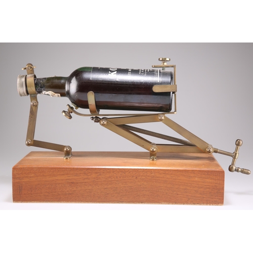 1B - A BRASS DECANTING CRADLE, with screw mechanism, on a hardwood plinth. Plinth 37.5cm wide