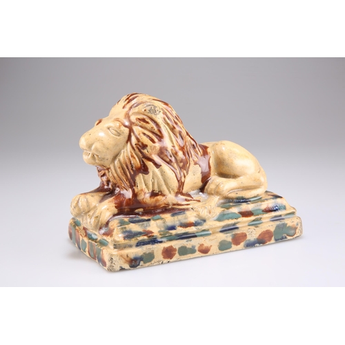 146 - A 19TH CENTURY POTTERY MODEL OF A RECUMBENT LION, on a stepped rectangular base, in mottled brown an... 