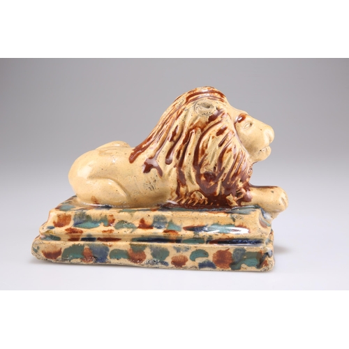 146 - A 19TH CENTURY POTTERY MODEL OF A RECUMBENT LION, on a stepped rectangular base, in mottled brown an... 