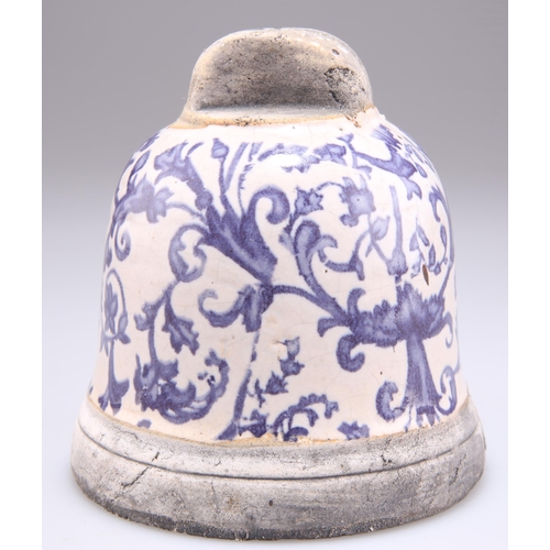 256 - A BLUE AND WHITE POTTERY BELL, blue painted with scrolling foliage. 10.5cm high