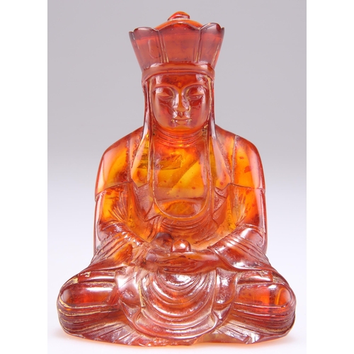 303 - AN AMBER COLOURED FIGURE OF A BUDDHA, modelled seated. 9.5cm high