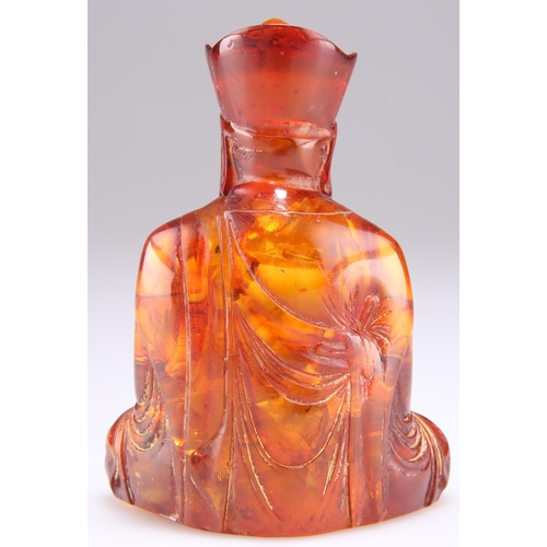 303 - AN AMBER COLOURED FIGURE OF A BUDDHA, modelled seated. 9.5cm high