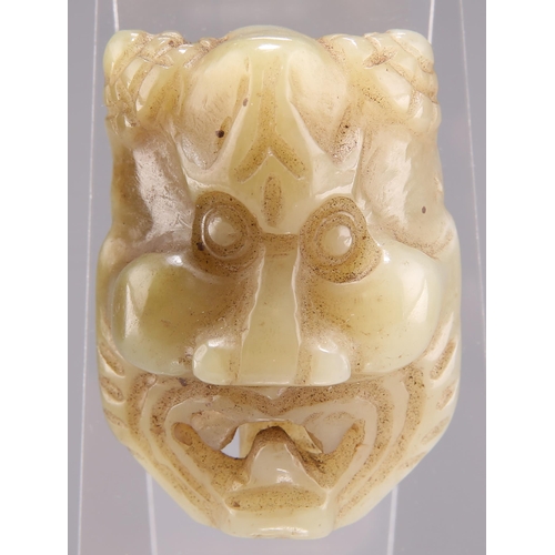 316 - A CHINESE CARVED JADE BELT BUCKLE, carved and pierced in the form of a mask, with an open mouth. 5.5... 