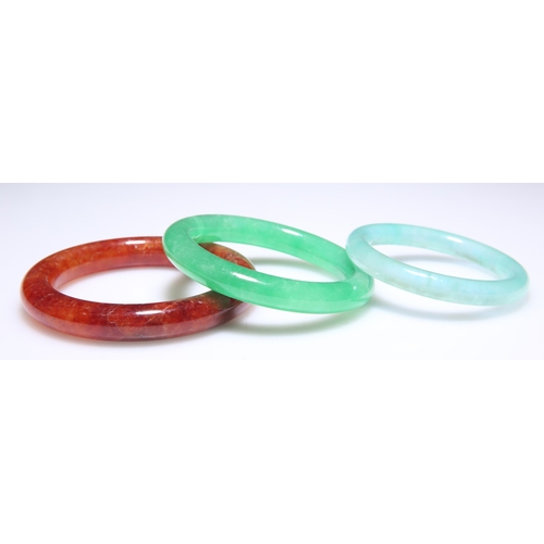 317 - THREE JADE BANGLES, comprising green, blue-green and red. (3) 6cm, 5.4cm and 6.5cm inner diameters r... 