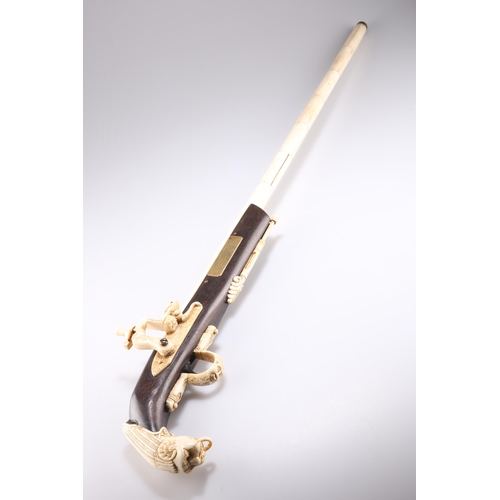 394 - A CARVED BONE AND WOOD CANE, in the form of a flintlock gun, with an applied brass plaque with prese... 