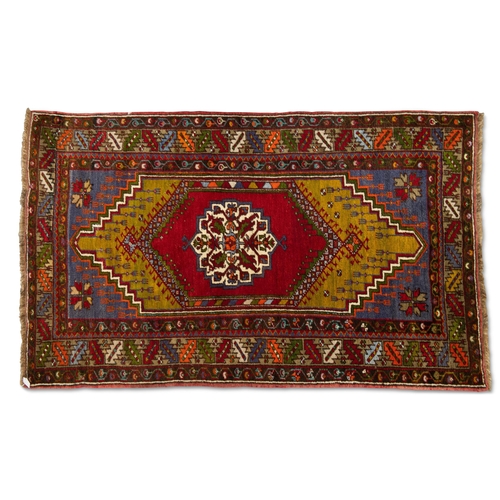 463 - A TURKISH RUG, hand-knotted and multicoloured, the dark red lozenge encloses a cream medallion withi... 