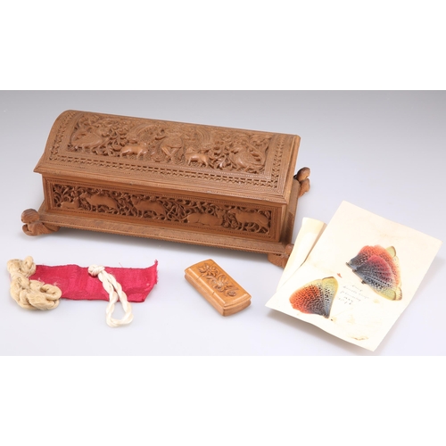 516 - AN INDIAN CARVED SANDALWOOD BOX, rectangular form with a domed casket lid and raised on four angel-f... 