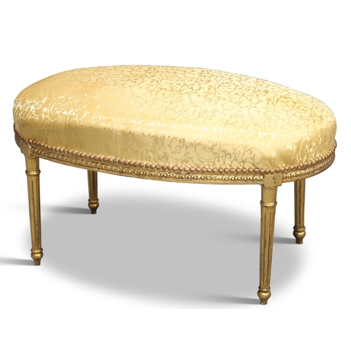 547 - A LOUIS XV STYLE GILDED AND UPHOLSTERED OVAL STOOL, raised on fluted tapering legs. Approx. 96cm lon... 