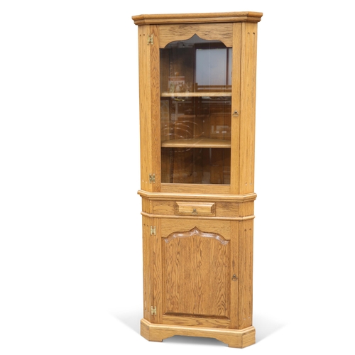 554 - A GEORGIAN STYLE OAK STANDING CORNER CABINET, with glazed upper section above a short drawer over a ... 